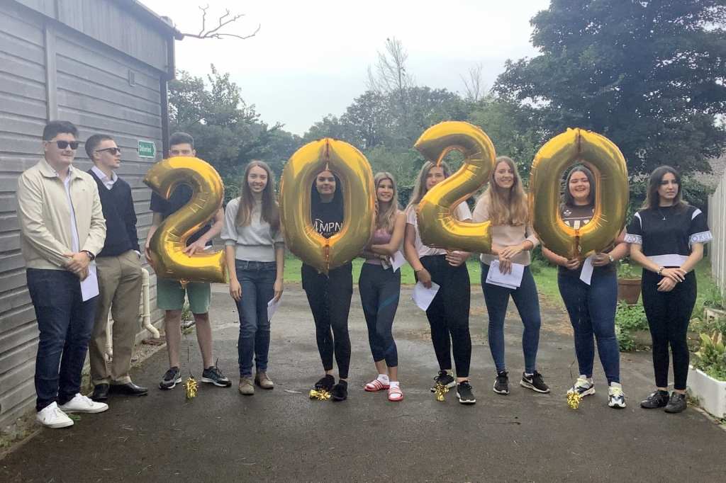 Teenage boys and girls holding up gold helium balloon numbers 2020